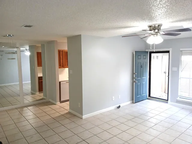 a view of a livingroom with a chandelier fan and windows