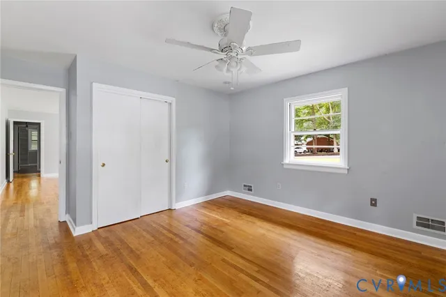 a view of a room with wooden floor and a ceiling fan