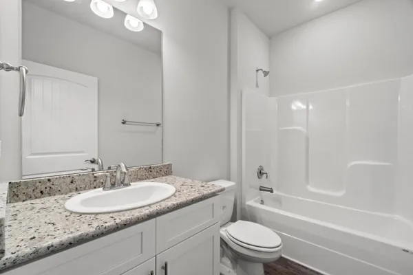 a bathroom with a granite countertop sink a toilet and a large mirror