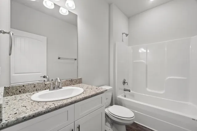a bathroom with a granite countertop sink a toilet and a large mirror