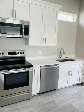 a kitchen with stainless steel appliances granite countertop a stove a microwave and white cabinets