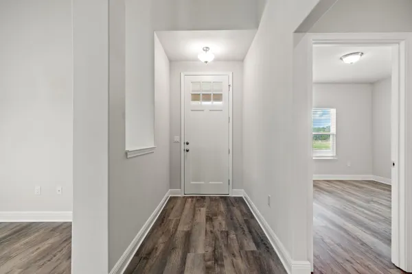 a view of a hallway with wooden floor and a bathroom