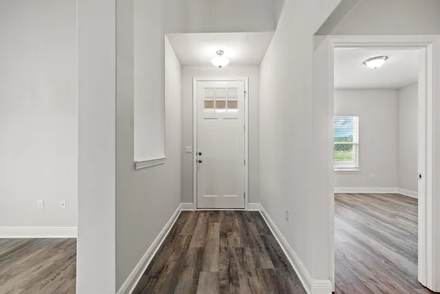 a view of a hallway with wooden floor and a bathroom