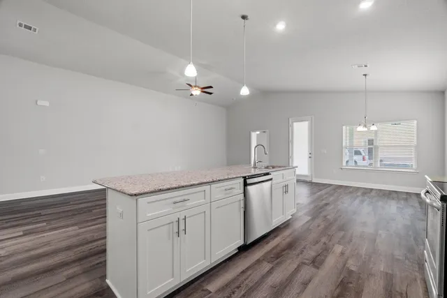 a large kitchen with granite countertop a large counter top a sink and cabinets