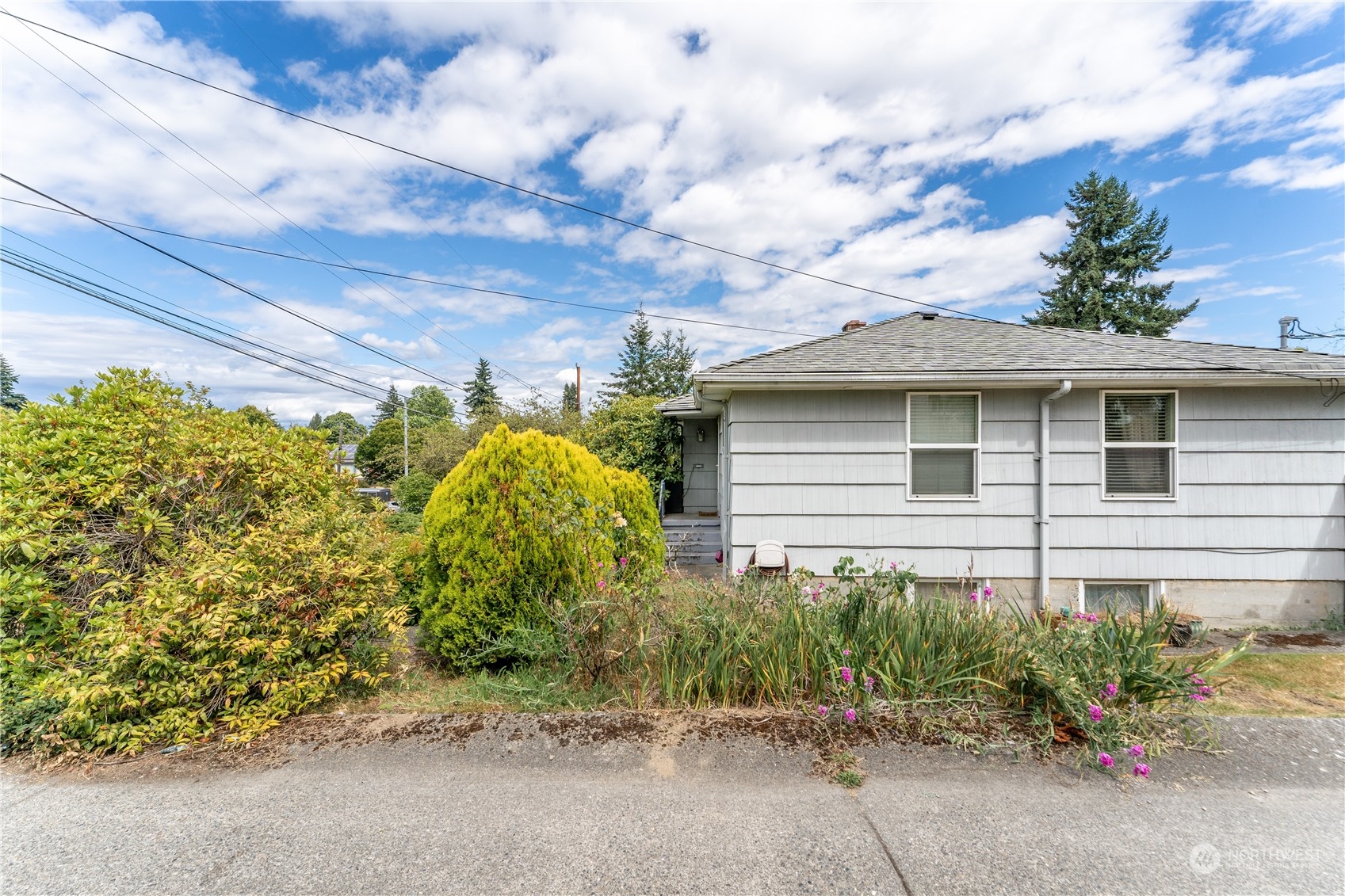 3509 Southwest Trenton Street Seattle, WA 98126 - Photo 2 of 23 a yellow house with flower garden in front of it