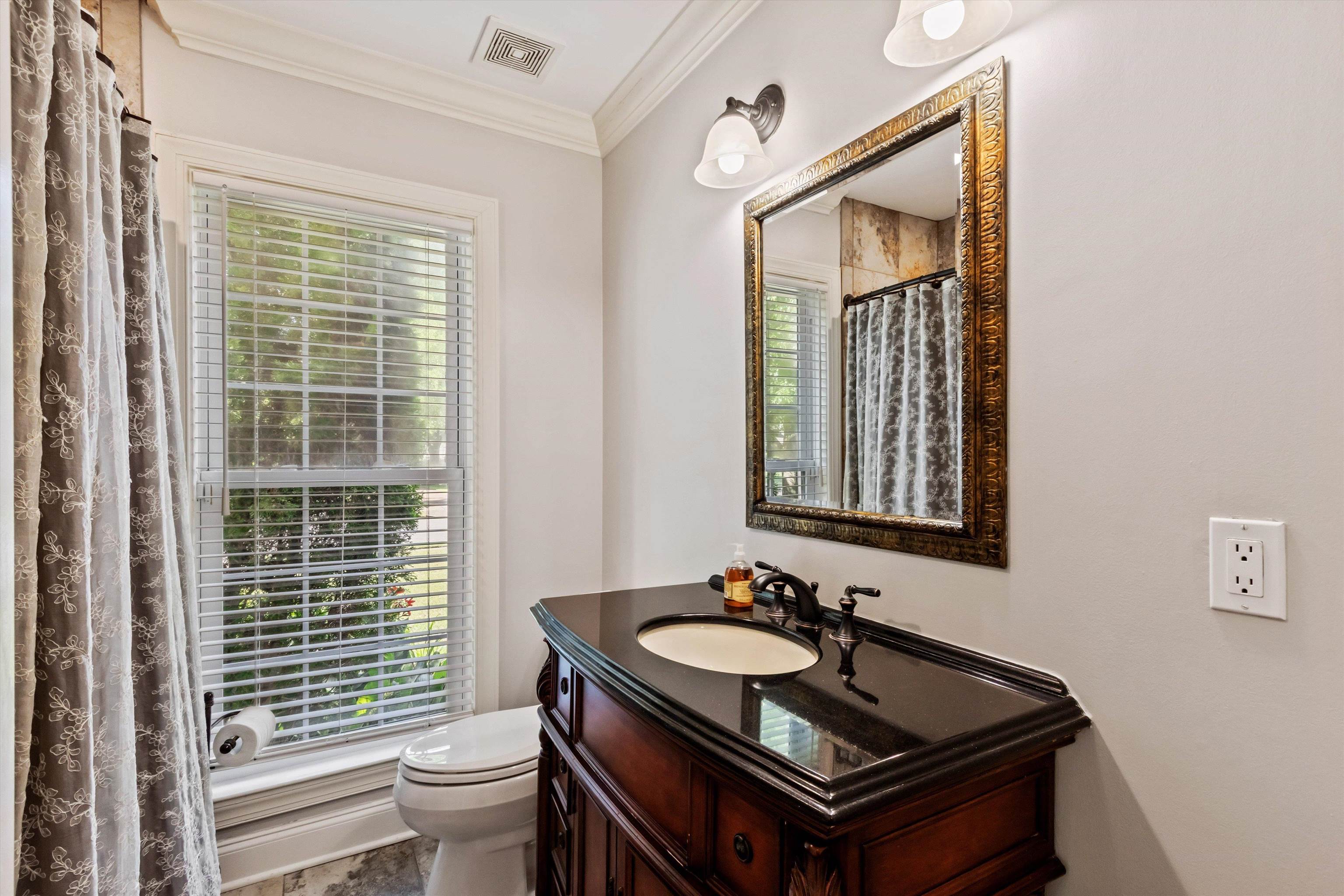 5302 South Angela Road Memphis, TN 38120 - Photo 25 of 40 Bathroom featuring a wood-finish vanity with an integrated sink and dark countertop, a decorative framed mirror, and a window with blinds