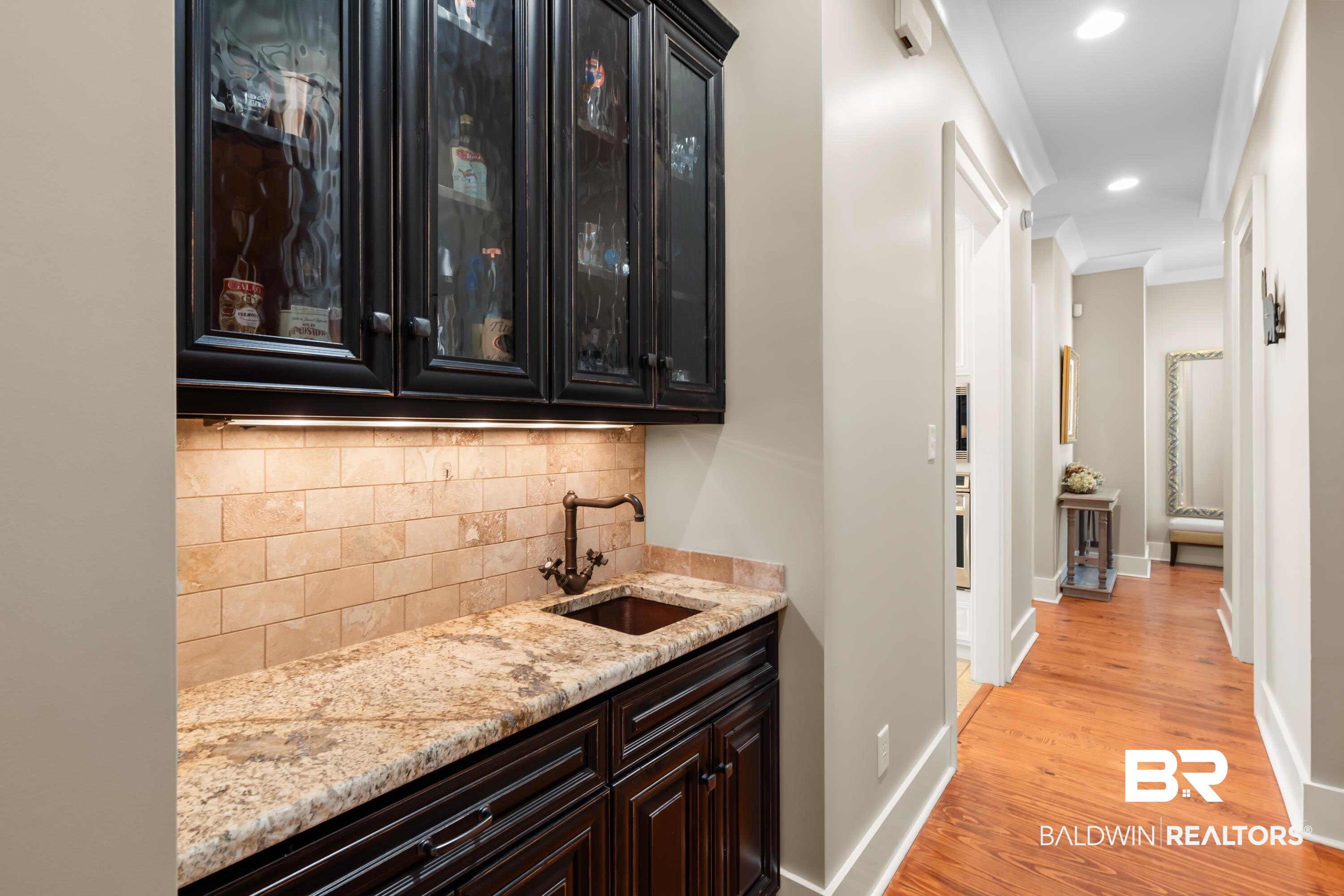 30057 Dolive Ridge Daphne, AL 36527 - Photo 17 of 55 Bar with light wood-type flooring, light stone counters, sink, backsplash, and dark brown cabinetry