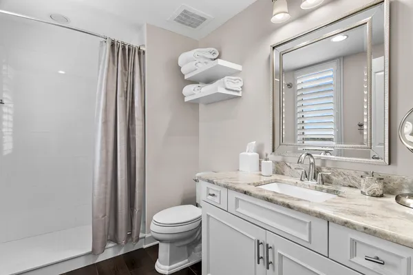 a bathroom with a granite countertop sink mirror and toilet