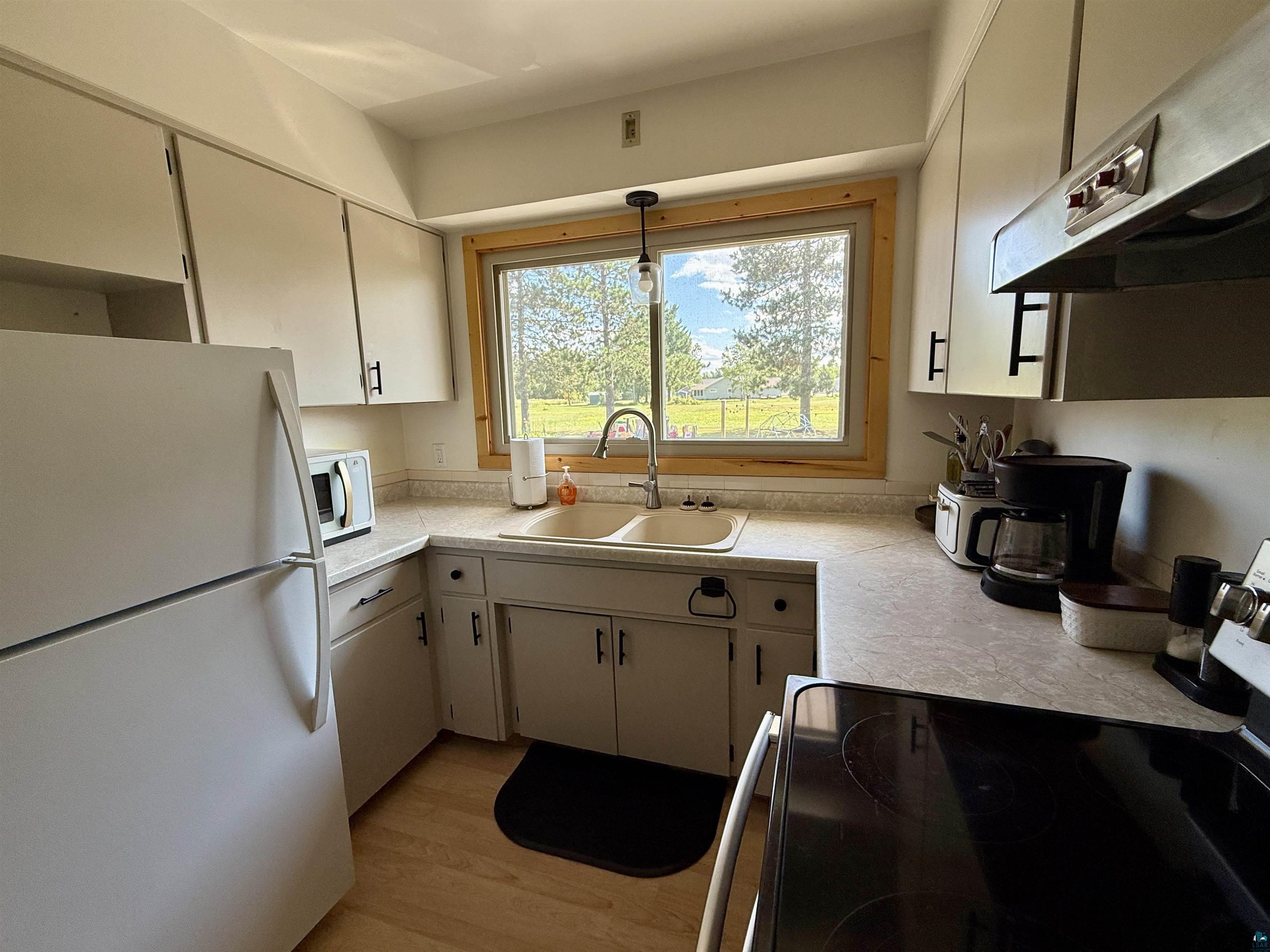 402 Alcohol Road Wrenshall, MN 55797 - Photo 10 of 24 Kitchen featuring light cabinetry with dark hardware, a double basin sink, light-toned countertops, and wood-finish flooring