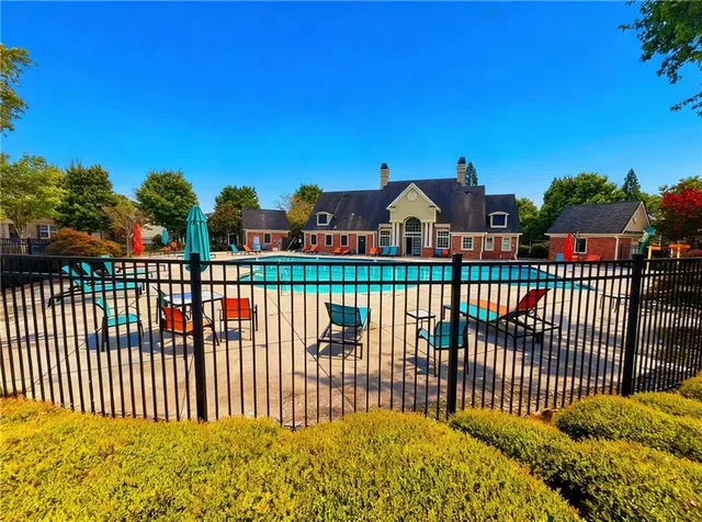a view of swimming pool with lawn chairs and plants