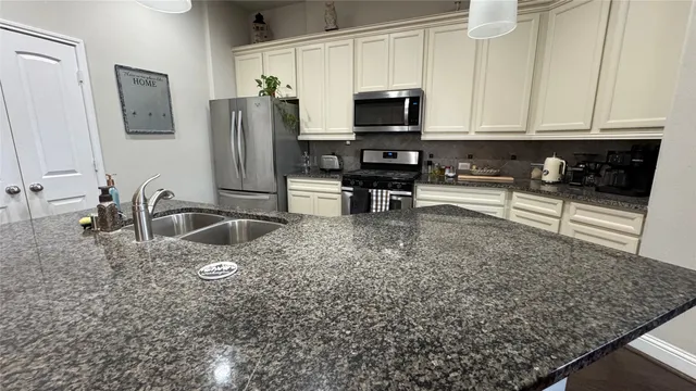 a kitchen with stainless steel appliances a sink a stove a microwave a refrigerator and cabinets