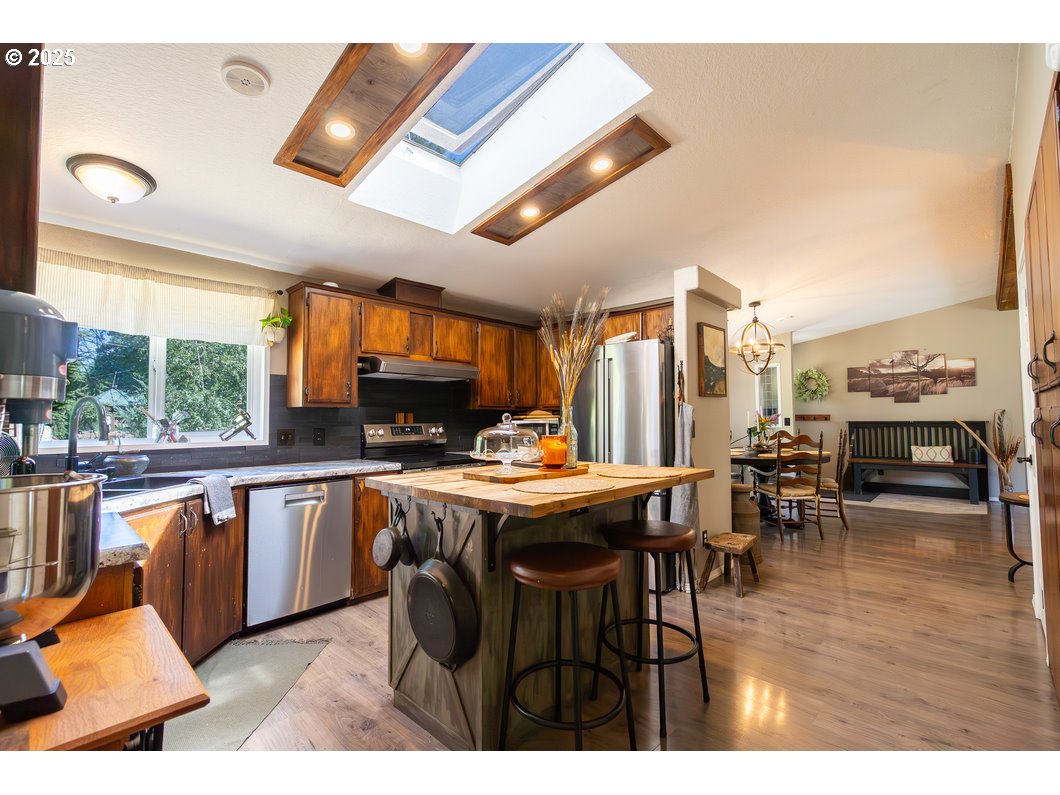 165 8th Place Mill City, OR 97360 - Photo 5 of 39 a kitchen with stainless steel appliances granite countertop a table chairs and a refrigerator