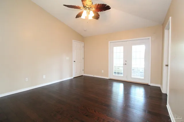 an empty room with wooden floor chandelier fan and windows