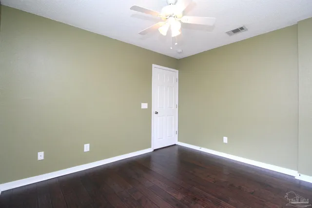 an empty room with a fan & a window