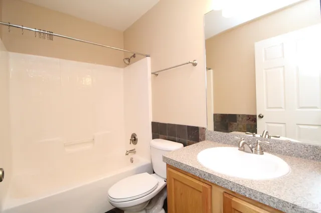 a bathroom with a granite countertop sink toilet a mirror and shower