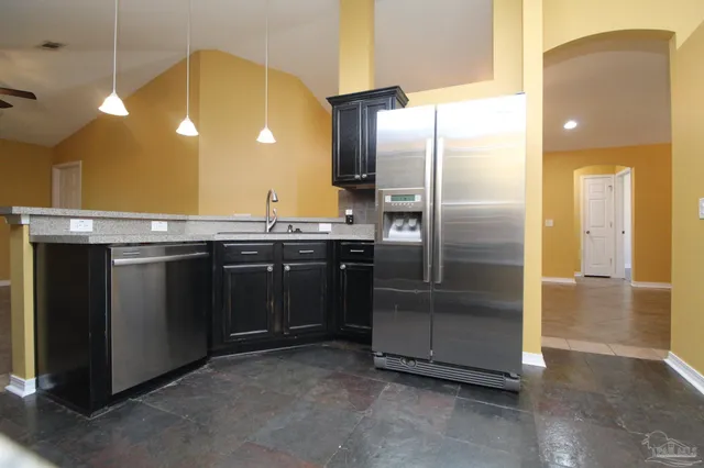 a kitchen with stainless steel appliances granite countertop a sink a refrigerator and a stove