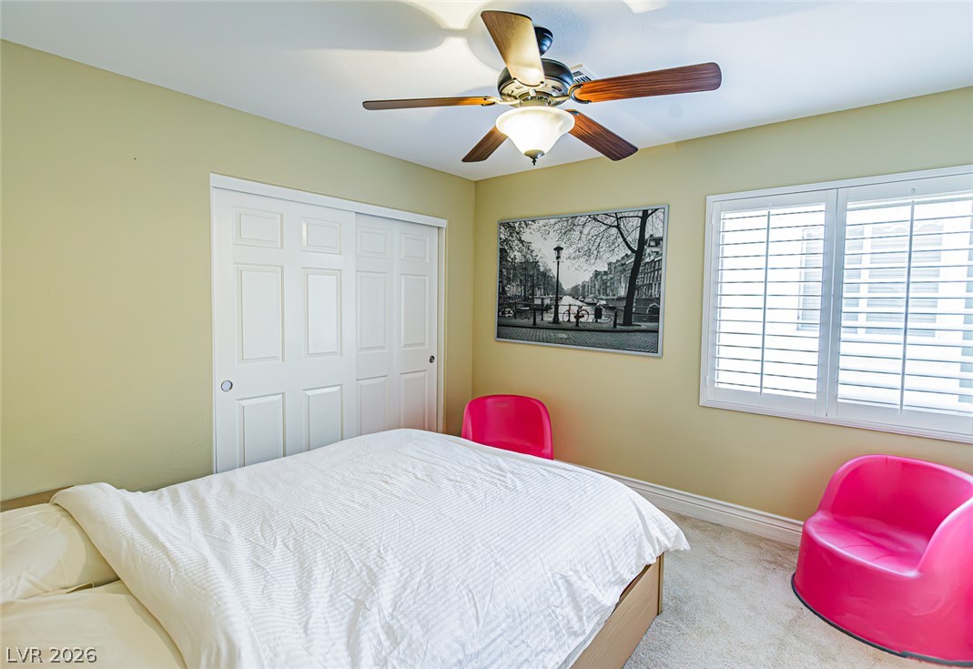 75 Tall Ruff Drive Las Vegas, NV 89148 - Photo 33 of 64 Plentiful natural light filters through plantation shutters into a carpeted secondary bedroom.