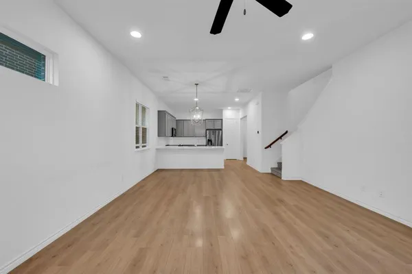 a view of a room with wooden floor chandelier and windows