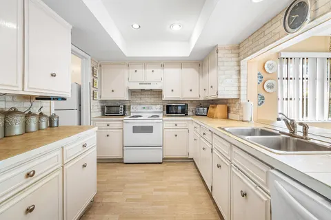 a kitchen with white cabinets sink and white appliances