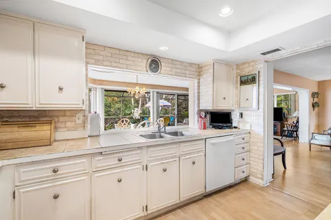a kitchen with white cabinets and sink