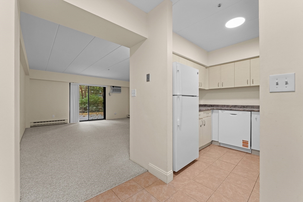 135 Pleasant Street, Unit 106 Brookline, MA 02446 - Photo 16 of 27 a view of a kitchen with white cabinets and a refrigerator