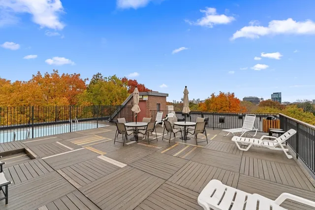 a view of a rooftop deck with chairs and wooden floor