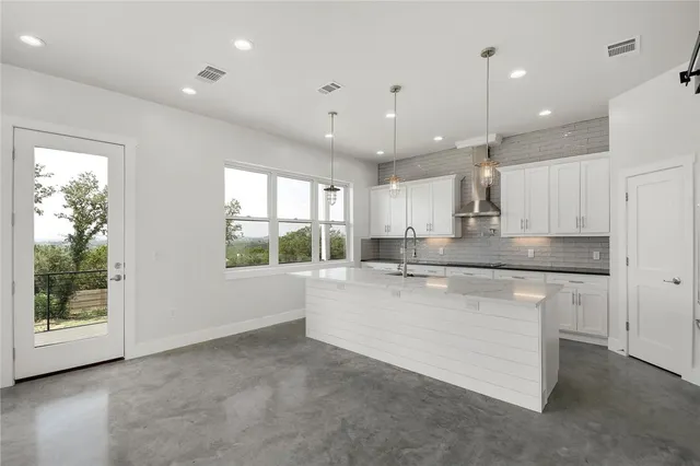 a large kitchen with stainless steel appliances kitchen island a large window a sink and a counter top space
