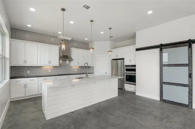 a large kitchen with stainless steel appliances kitchen island a large counter top and stove top oven