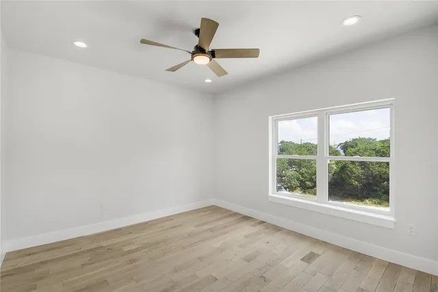 an empty room with wooden floor fan and windows