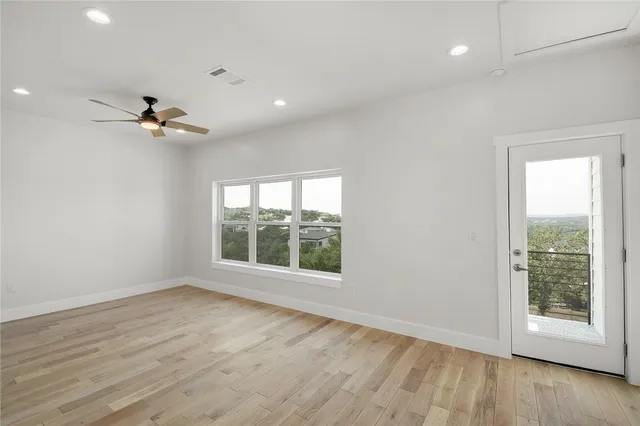 a view of an empty room with a window and wooden floor