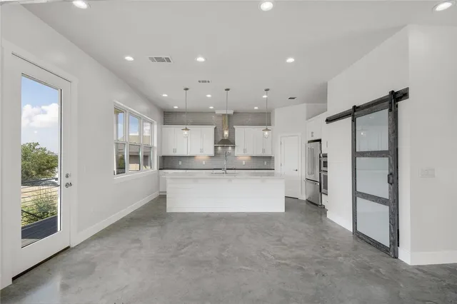 a large kitchen with stainless steel appliances kitchen island a large counter top and a refrigerator
