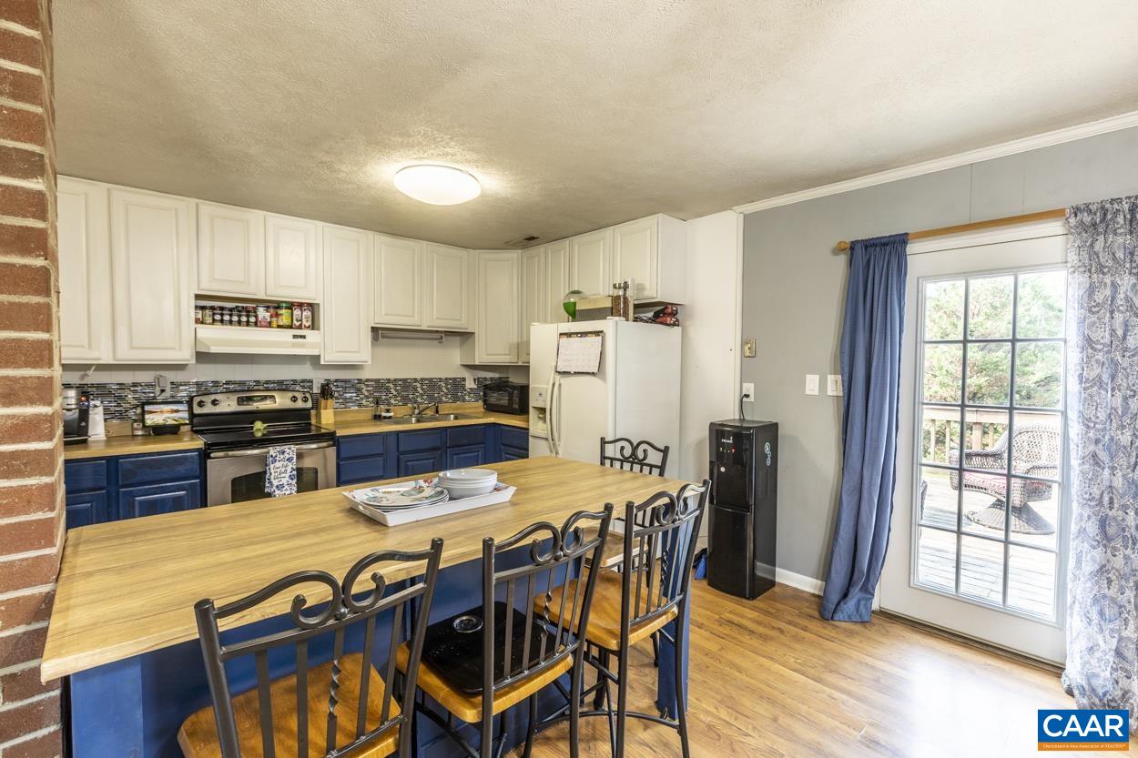 4764 Amicus Road Ruckersville, VA 22968 - Photo 17 of 33 a kitchen with stainless steel appliances kitchen island granite countertop a stove a refrigerator a sink a dining table and chairs with wooden floor
