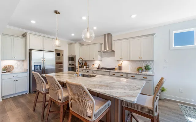 a kitchen with stainless steel appliances granite countertop a stove a refrigerator a kitchen island a table and chairs
