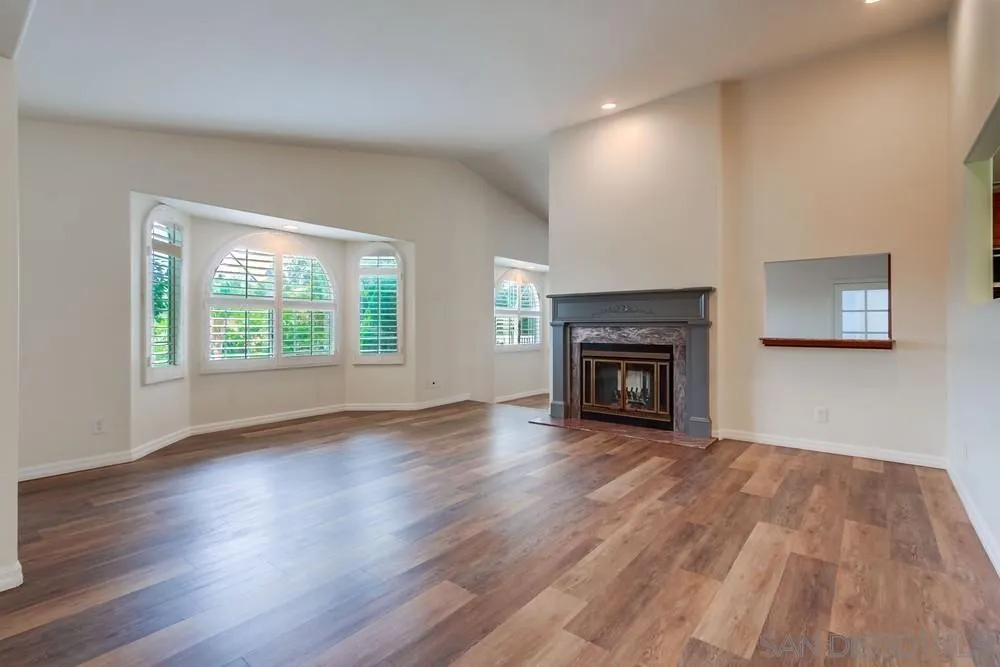 227 Hutchison Street Vista, CA 92084 - Photo 11 of 58 an empty room with wooden floor fireplace and windows