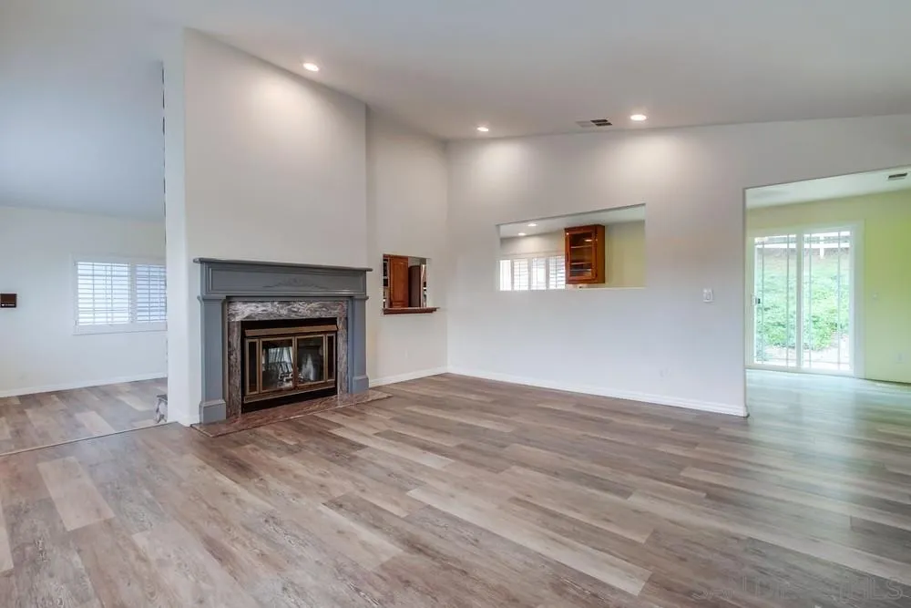 227 Hutchison Street Vista, CA 92084 - Photo 12 of 58 an empty room with wooden floor a fireplace and windows