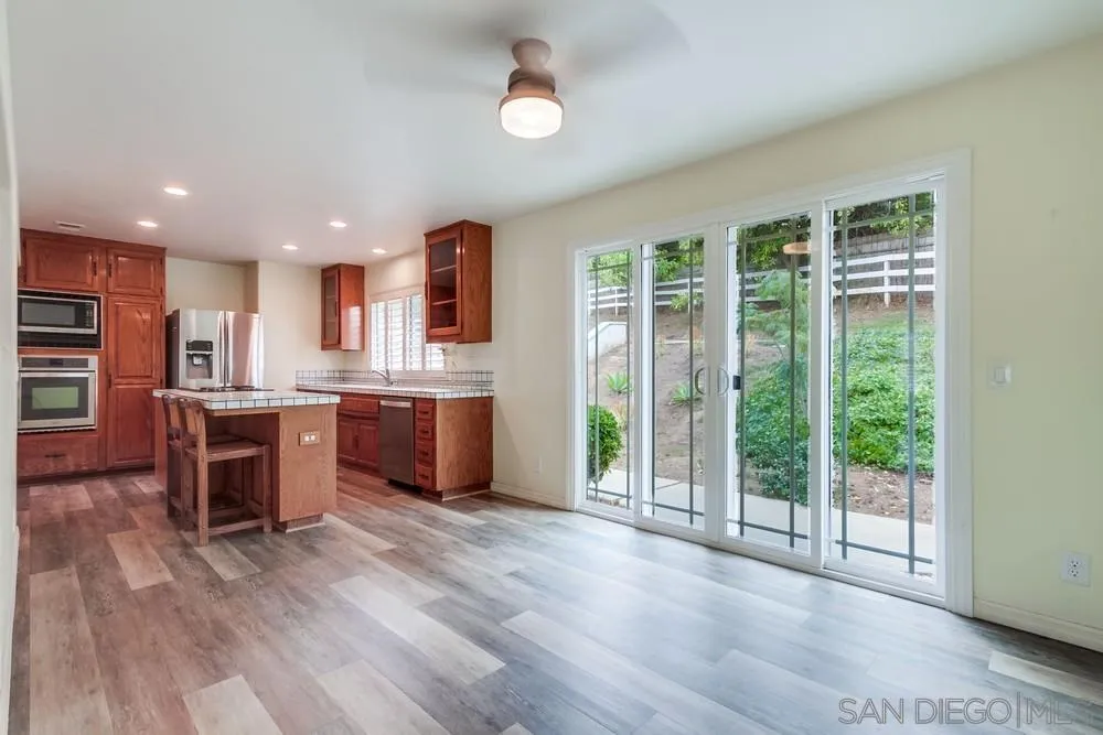 227 Hutchison Street Vista, CA 92084 - Photo 15 of 58 a open kitchen with kitchen island wooden cabinets and a refrigerator