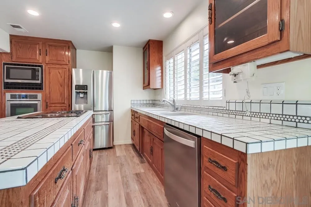 227 Hutchison Street Vista, CA 92084 - Photo 17 of 58 a kitchen with stainless steel appliances granite countertop a sink a stove and a wooden cabinets