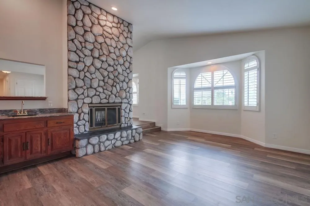 227 Hutchison Street Vista, CA 92084 - Photo 22 of 58 an empty room with wooden floor a fireplace and windows