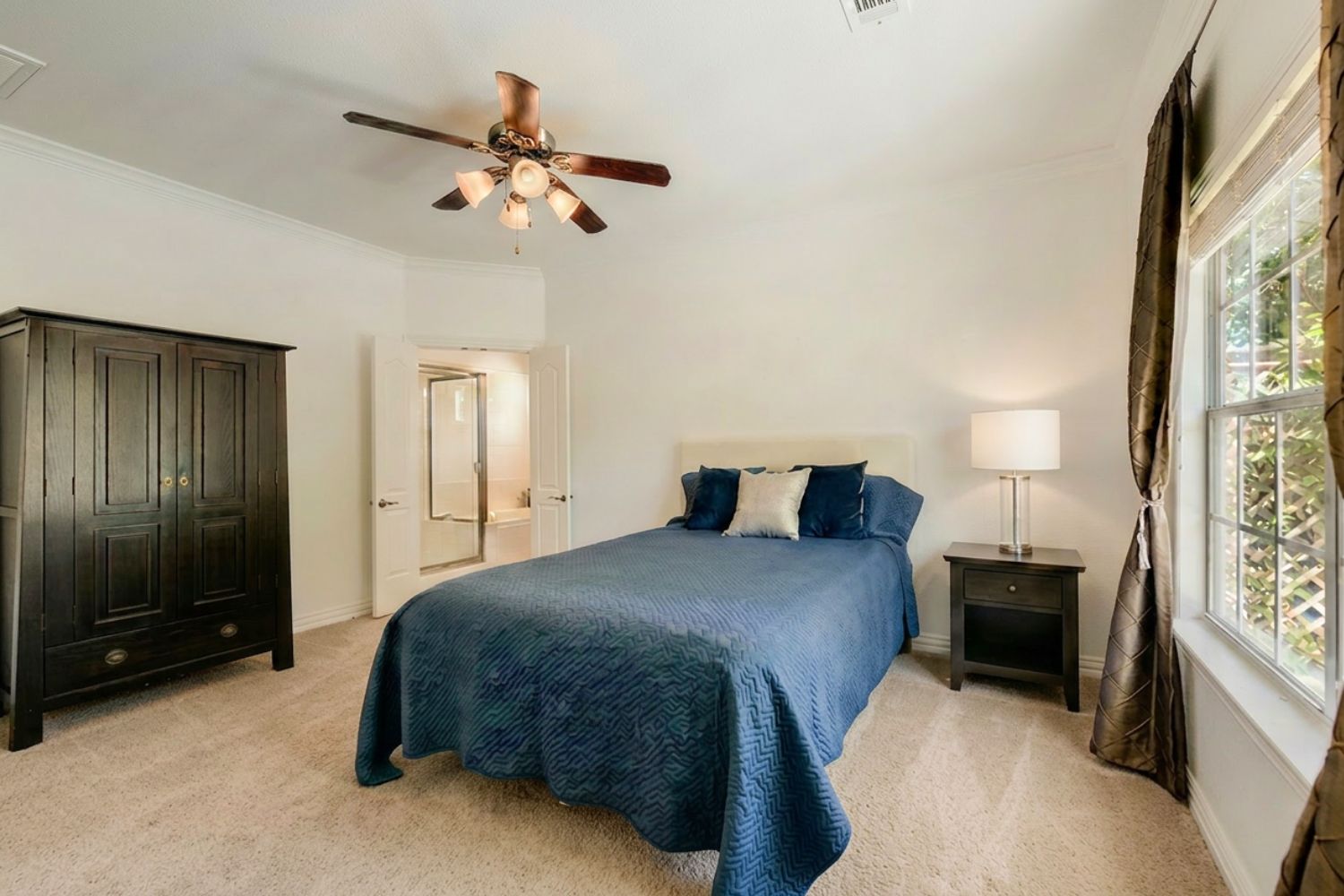 6715 Windrift Way, Unit 28 Austin, TX 78745 - Photo 13 of 19 A well-lit bedroom features plush carpeting and convenient access to an en-suite bathroom.