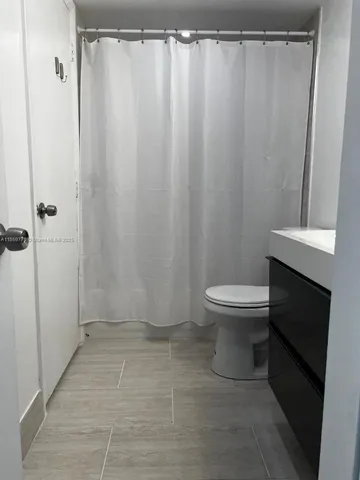 a bathroom with a toilet and a shower curtain