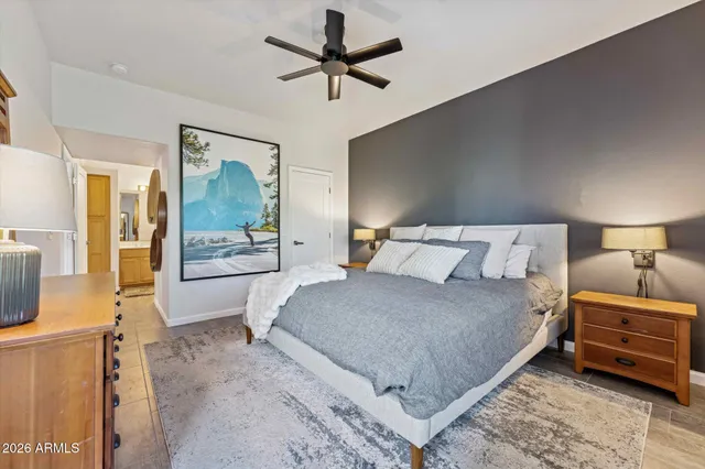 a bedroom with a large bed and a chandelier fan