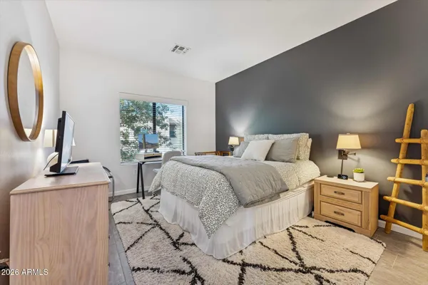 a bedroom with a bed a mirror and lamp next to a window