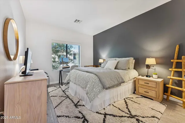 a bedroom with a bed a mirror and lamp next to a window