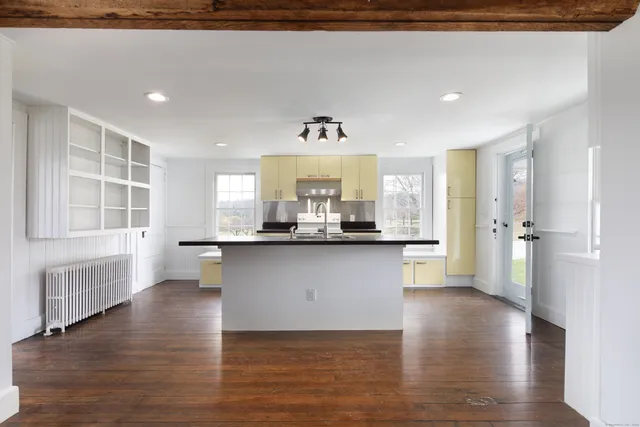 a living room with kitchen island granite countertop wooden floors and a fireplace