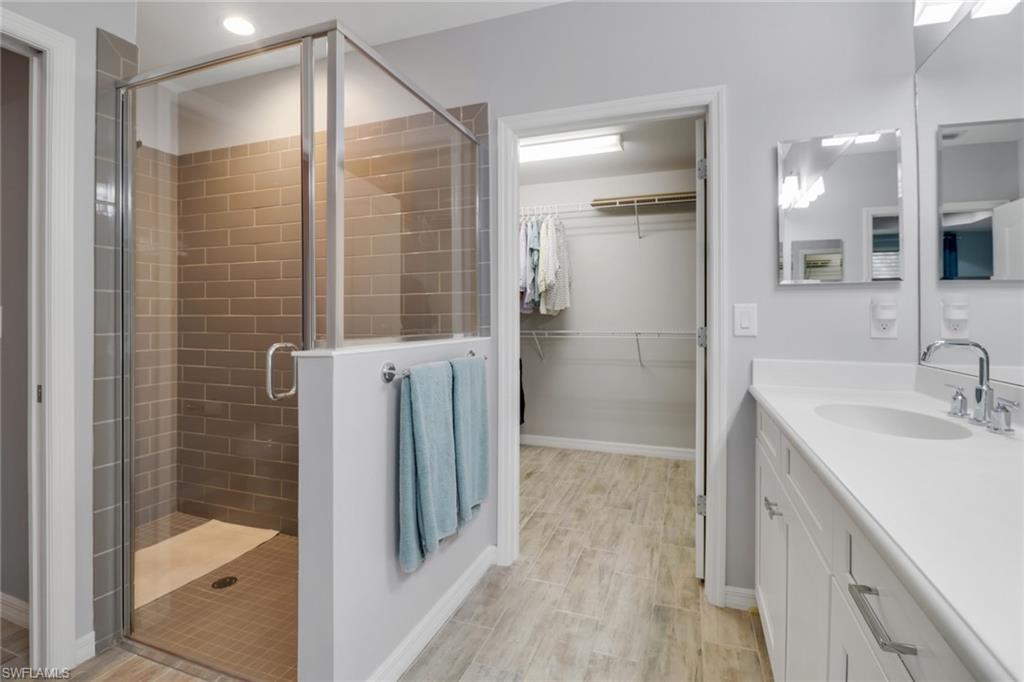 6973 Avalon Circle, Unit 1403 Naples, FL 34112 - Photo 19 of 37 Full bath with vanity, a shower stall, a spacious closet, and wood finish floors
