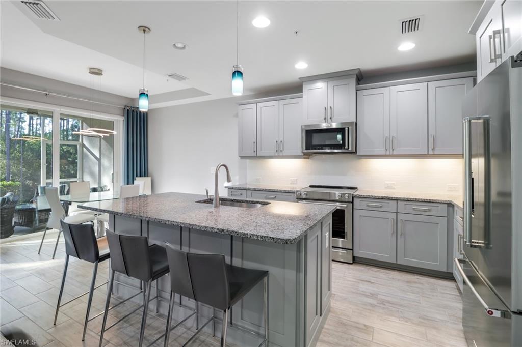 6973 Avalon Circle, Unit 1403 Naples, FL 34112 - Photo 2 of 37 Kitchen with stainless steel appliances, light stone counters, decorative light fixtures, gray cabinets, and recessed lighting