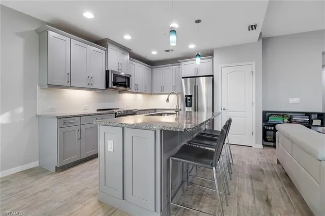a kitchen with kitchen island granite countertop wooden floors white cabinets and stainless steel appliances