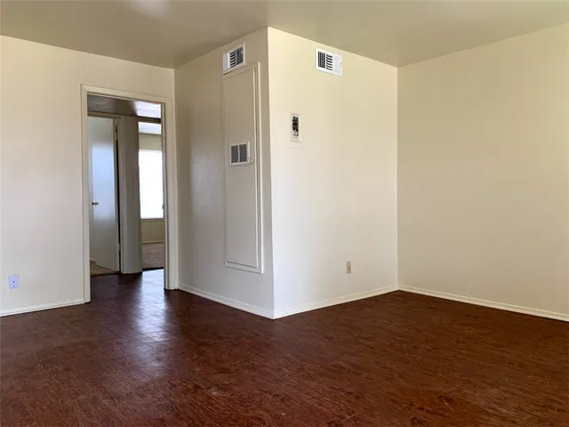a view of an empty room with wooden floor and closet