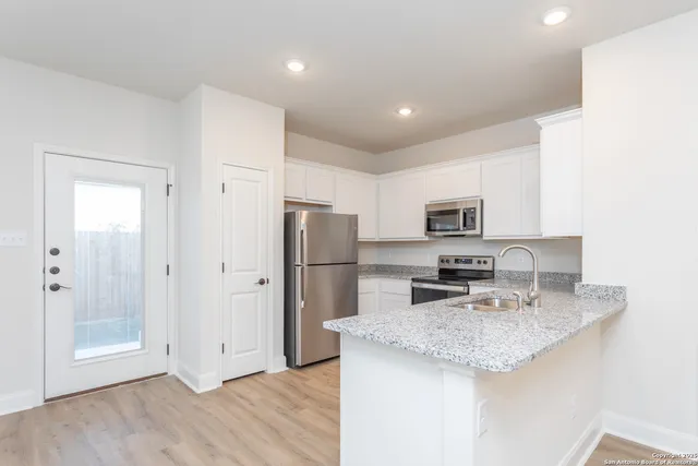 a kitchen with stainless steel appliances granite countertop a refrigerator a sink a stove a microwave and island