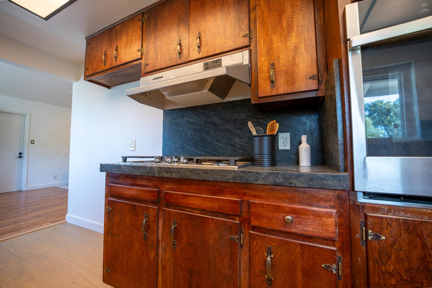 4220 Elva Way Sacramento, CA 95821 - Photo 7 of 52 a kitchen with granite countertop wooden cabinets and a wooden floor